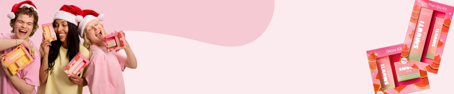Three people wearing Santa hats holding Smuuti Skin holiday sets against a pink background