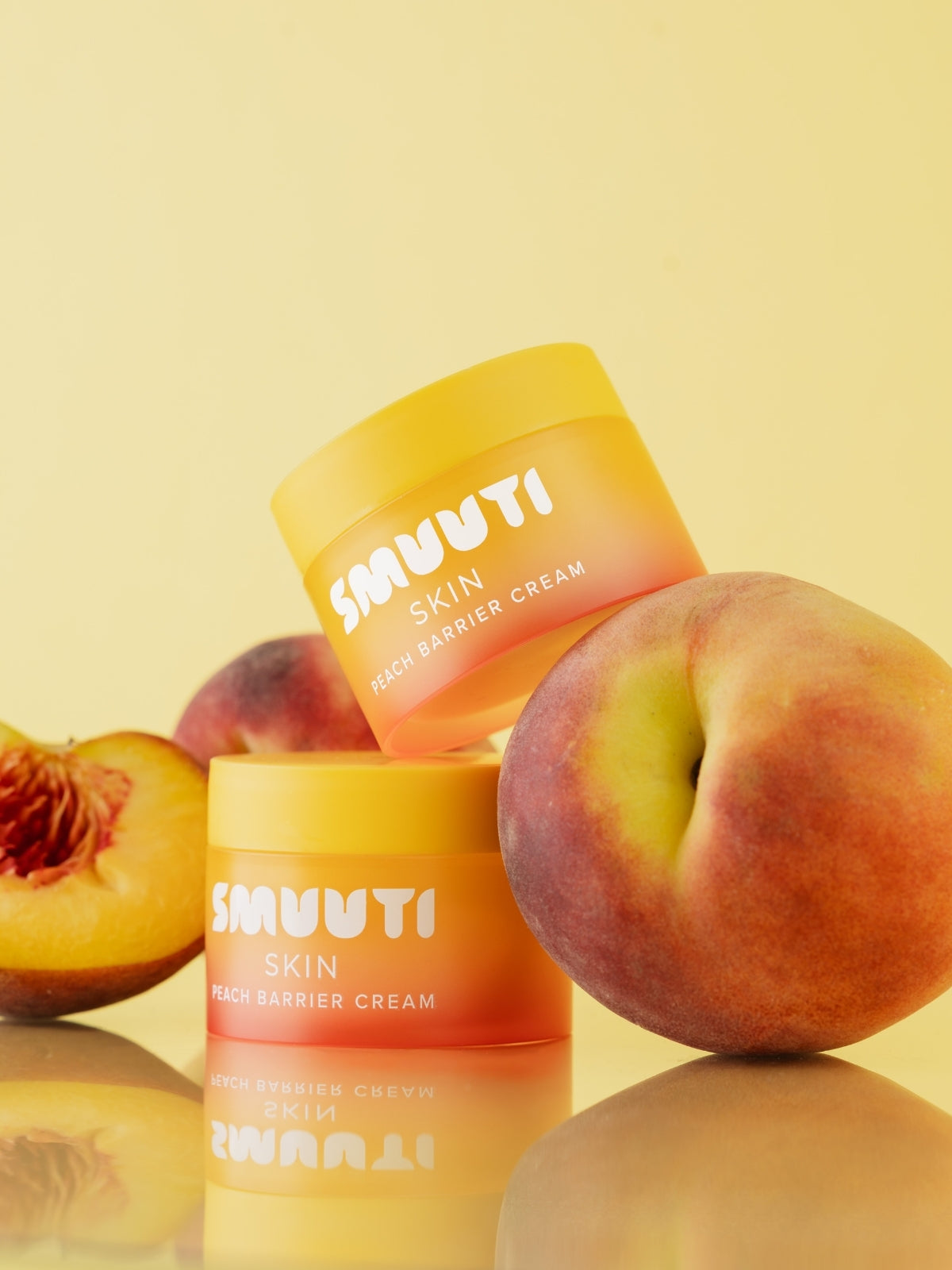 Two jars of SMUUTI Skin Peach Barrier Cream with peaches on a yellow background
