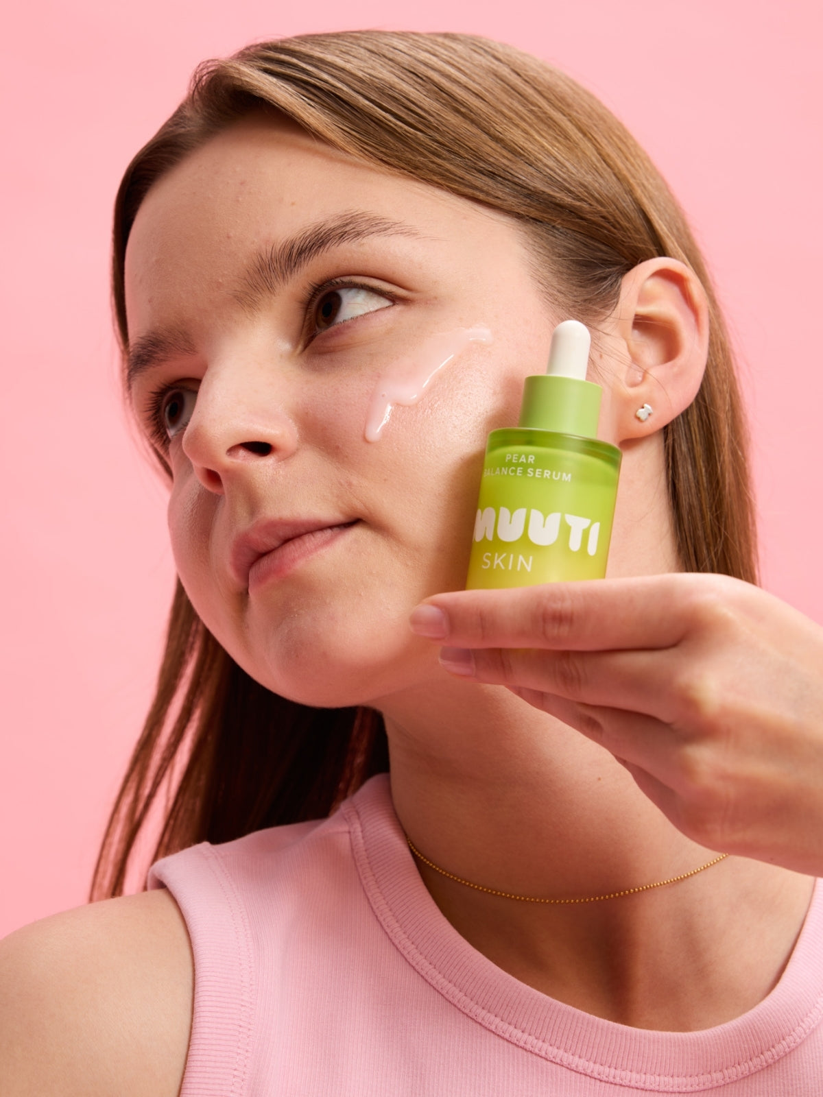 Woman applying Smuuti Skin pear balance serum to her face with a pink background