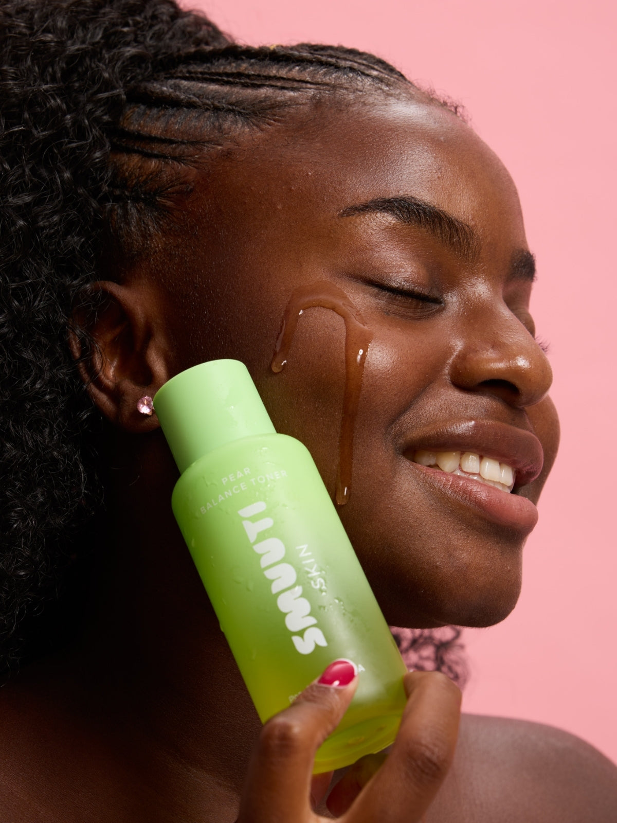 Woman applying Smuuti Skin pear balance toner to her face with a pink background