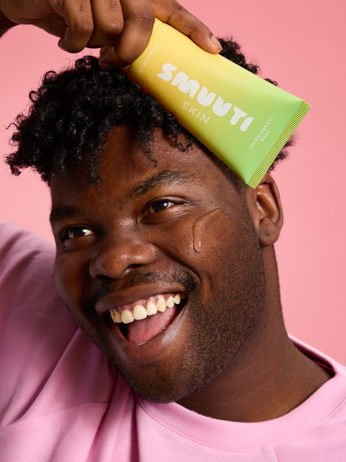 Person applying Smuuti Skin pear cleansing gel against a pink background