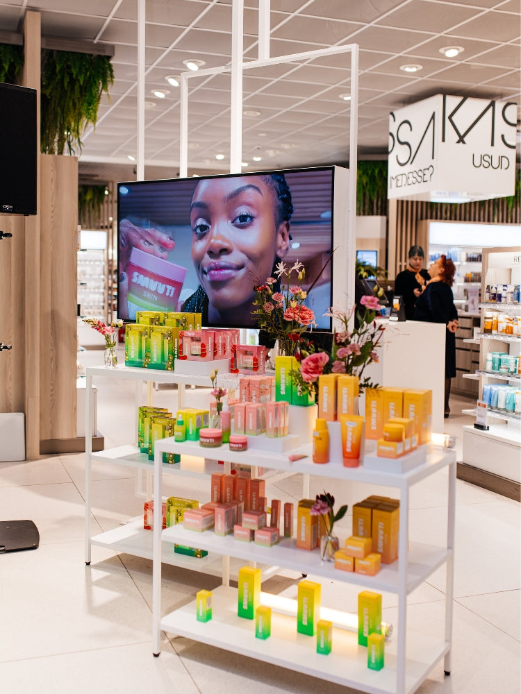 Display of Smuuti Skin skincare products with a television screen showing a person in a store setting.