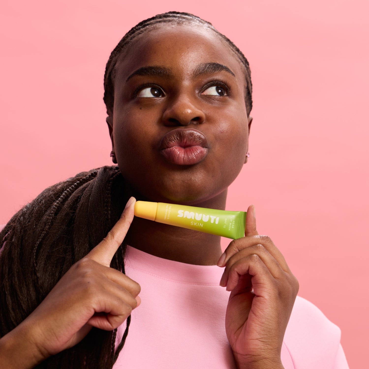 Woman holding smuuti skin pear lip mask against a pink background