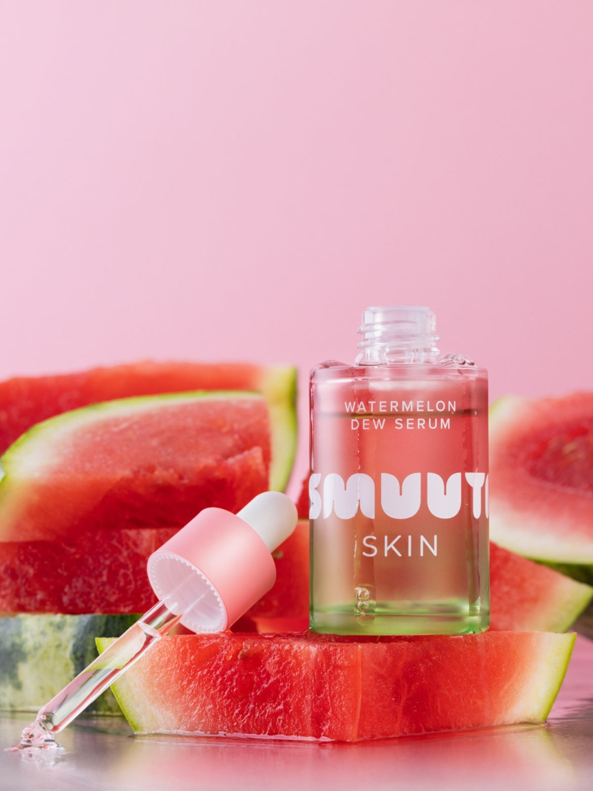 Smuuti Skin Watermelon dew serum bottle with watermelon slices on a pink background
