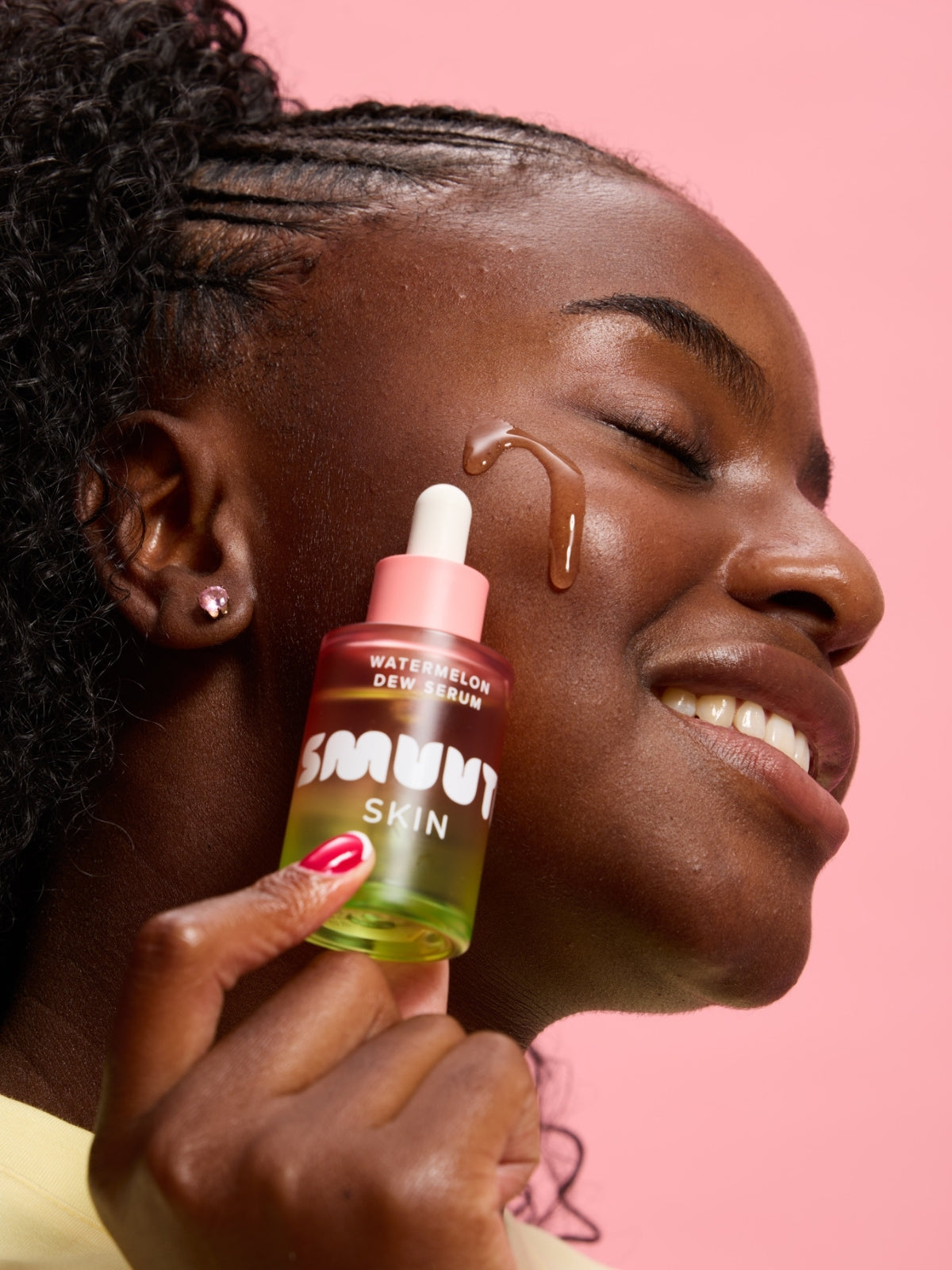 Woman applying Smuuti Skin watermelon dew serum to her face with a pink background