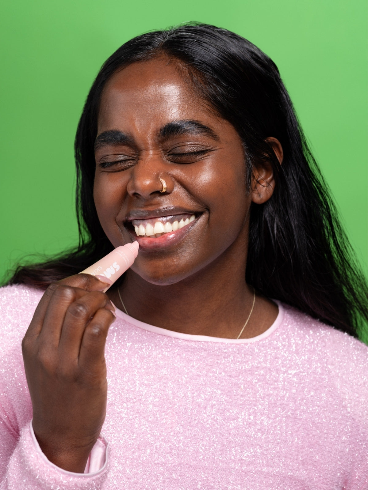 model applying Smuuti Skin watermelon lip mask on a green background