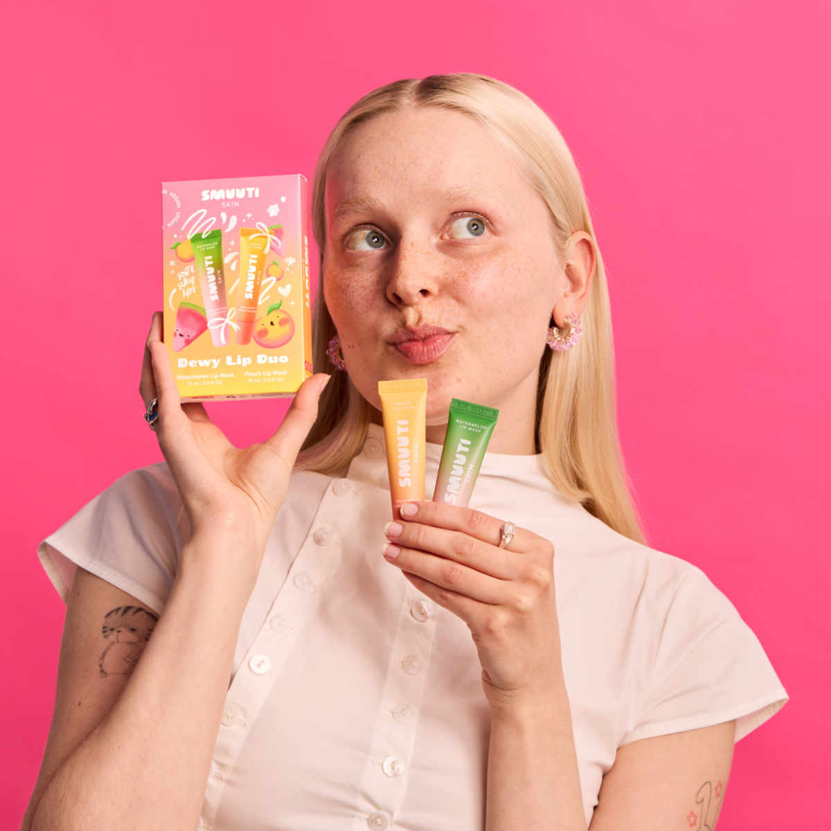 A woman with blonde hair holds up the dewy lip duo set and two lip masks