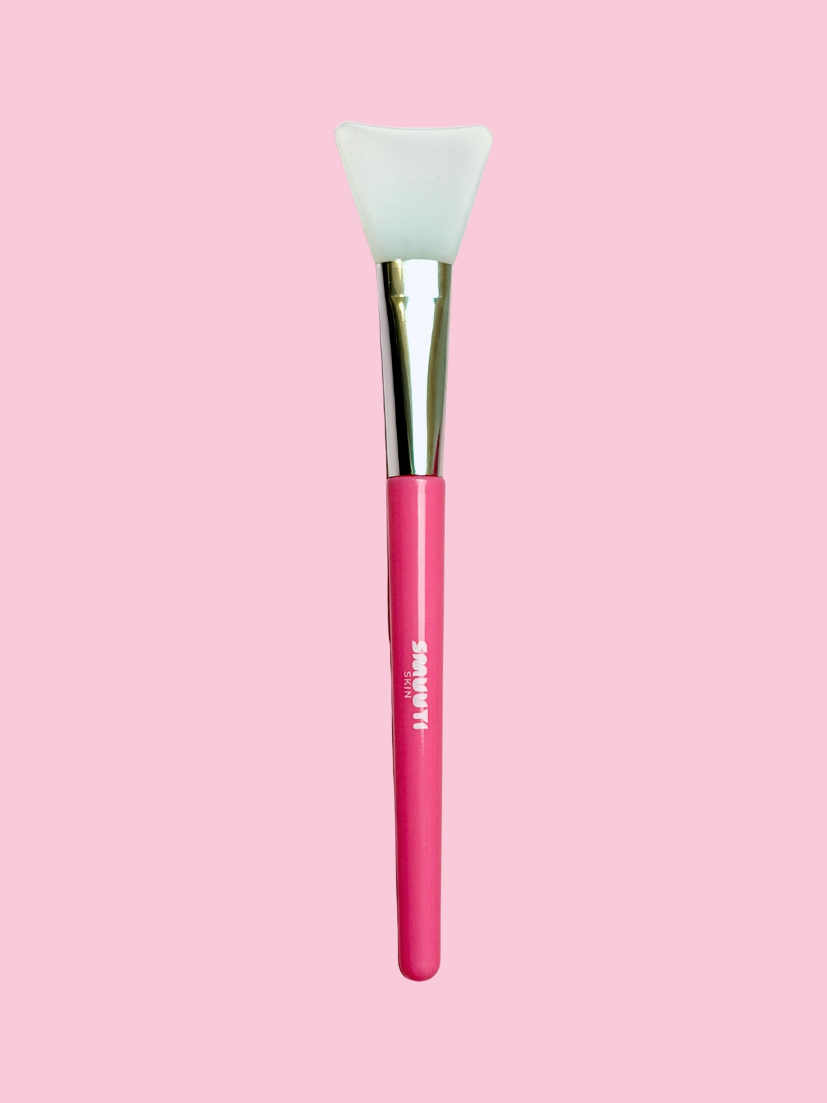 Pink face mask spatula with a white silicone head on a pink background