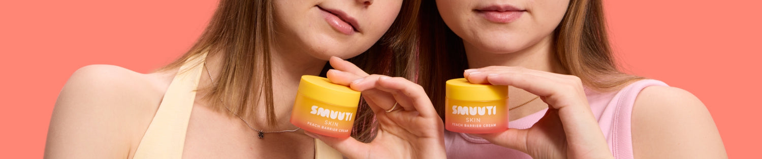 Two people holding peach barrier creams against a coral background