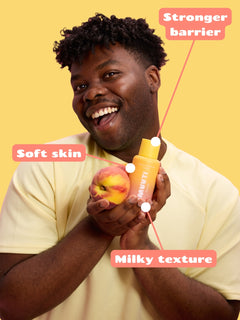 Person holding a peach and Smuuti Skin peach barrier toner on a yellow background