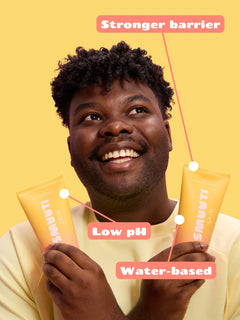 Man holding two tubes of Smuuti Skin peach cleansing cream with text on a yellow background