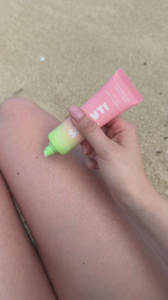 Smuuti Skin watermelon sun cream being applied onto person's leg in a heart shape on a beach