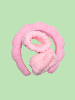 Pink fuzzy headband and wrist cuffs on a light green background