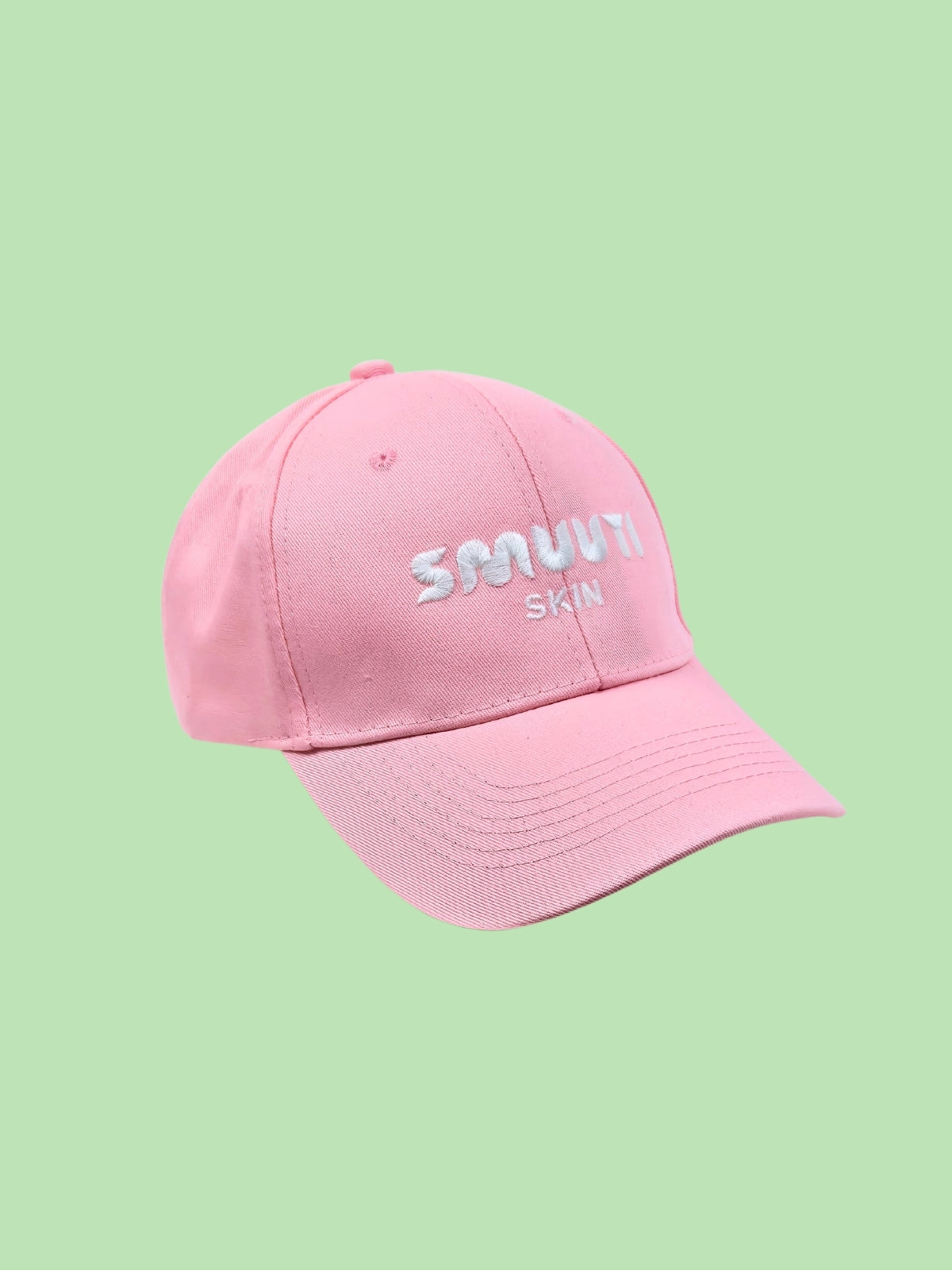Pink cap with the Smuuti Skin logo on a light green background