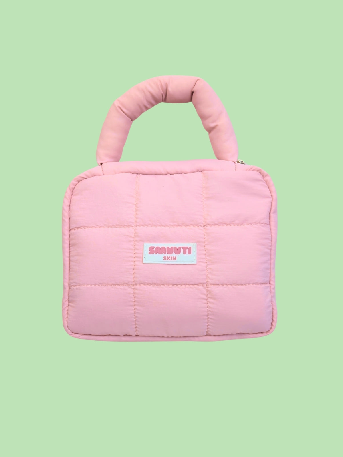 Pink quilted handbag with a Smuuti Skin logo label on a light green background