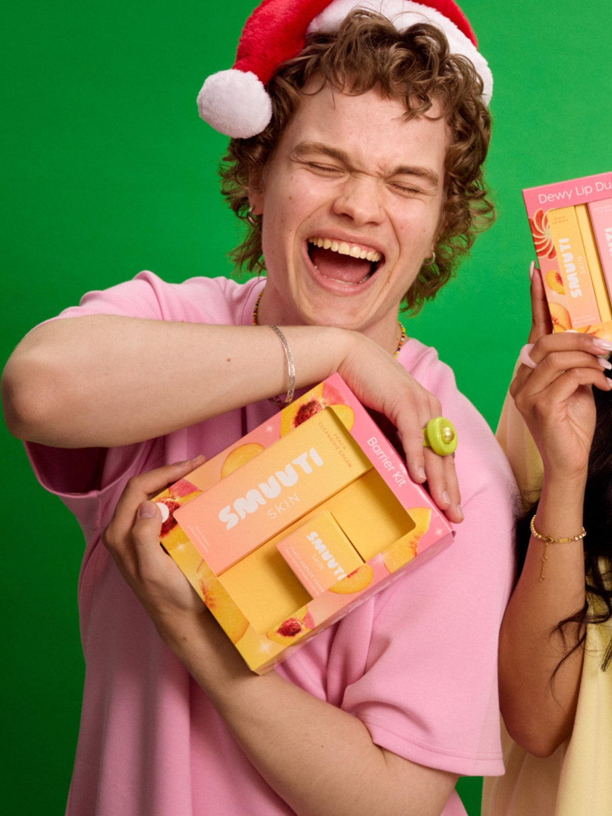Person wearing a Santa hat holding a Smuuti Skin barrier kit on a green background