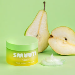 Jar of SMUUTI Skin Pear Cleansing Balm with a pear and its half on a green background