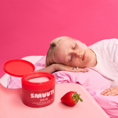 A person in a pink outfit lies on a pink bed with a strawberry boost toner pads.